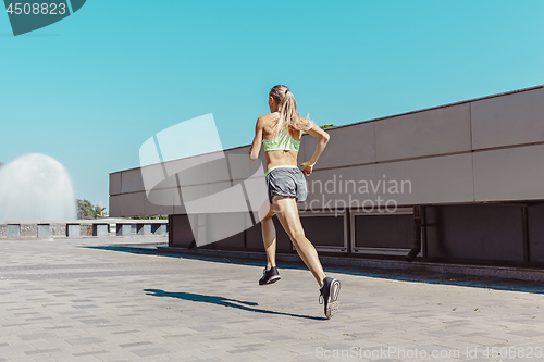 Image of Pretty sporty woman jogging at city