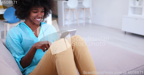 Image of african american woman at home using digital tablet