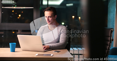 Image of man working on laptop in dark office