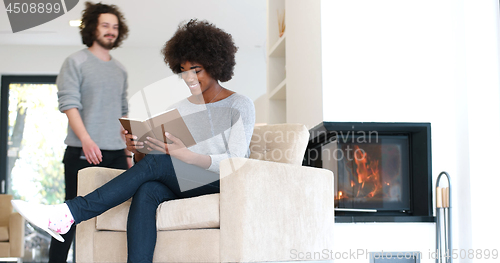 Image of multiethnic couple hugging in front of fireplace