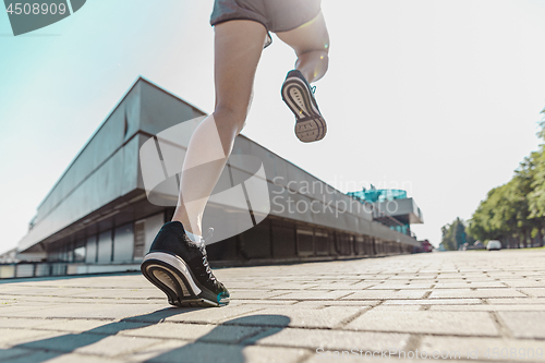 Image of Pretty sporty woman jogging at city