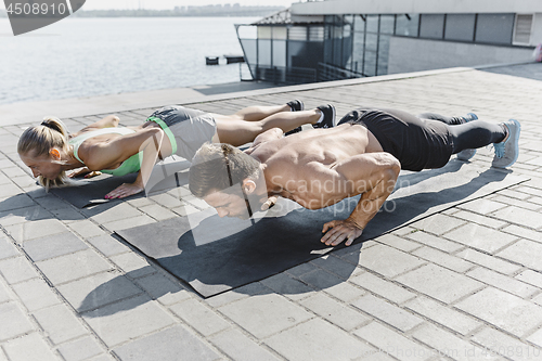 Image of Fit fitness woman and man doing fitness exercises outdoors at city