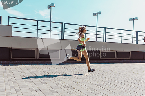 Image of Pretty sporty woman jogging at city