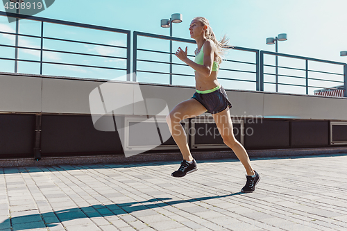 Image of Pretty sporty woman jogging at city