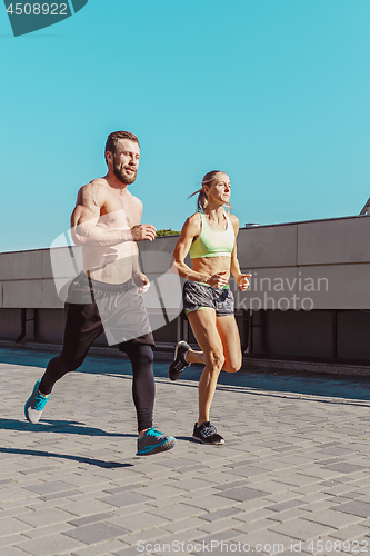 Image of Pretty sporty woman and man jogging at city