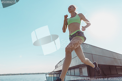Image of Pretty sporty woman jogging at city
