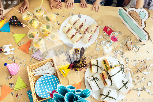 Image of Girl birthday decorations. table setting from above with cakes, drinks and party gadgets.