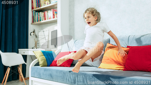 Image of Little surprised teen girl watching tv at home.