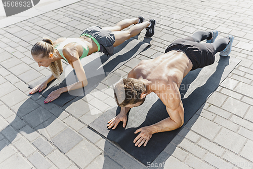 Image of Fit fitness woman and man doing fitness exercises outdoors at city