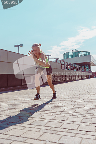 Image of Pretty sporty woman jogging at city