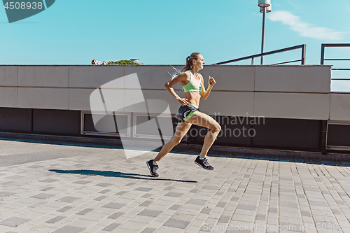 Image of Pretty sporty woman jogging at city