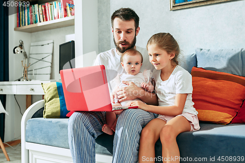 Image of Proud father holding his baby daughters at home