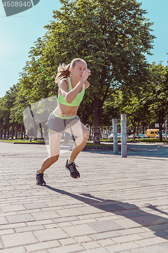 Image of Pretty sporty woman jogging at city