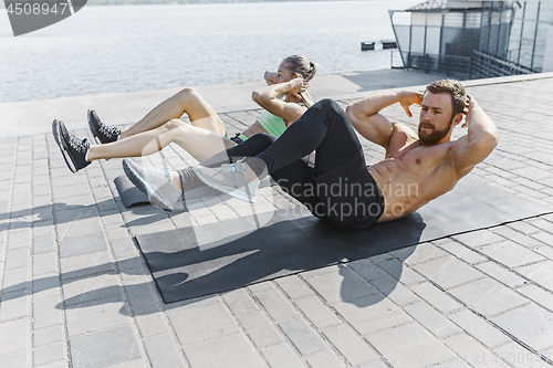 Image of Fit fitness woman and man doing fitness exercises outdoors at city