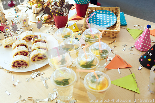 Image of Girl birthday decorations. table setting from above with cakes, drinks and party gadgets.