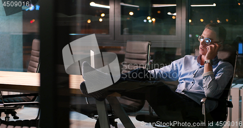 Image of businessman sitting with legs on desk at office