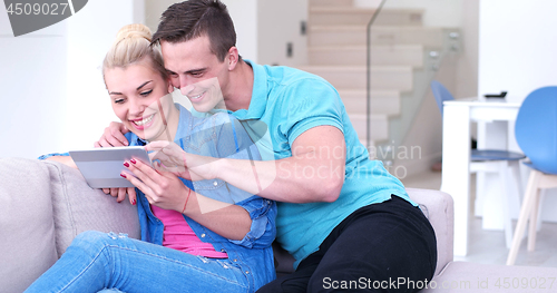 Image of couple relaxing at  home with tablet computers