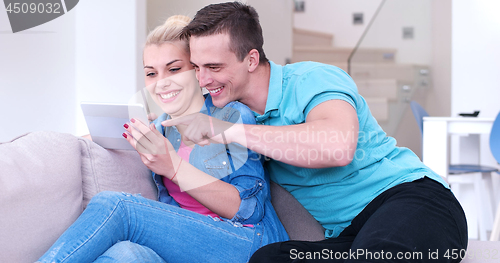 Image of couple relaxing at  home with tablet computers