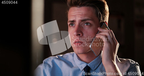 Image of man using mobile phone in dark office