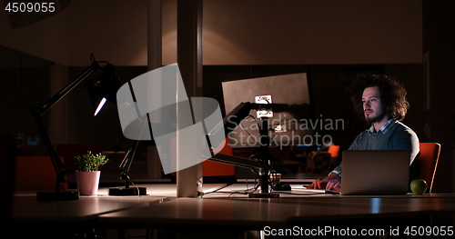 Image of man working on computer in dark office