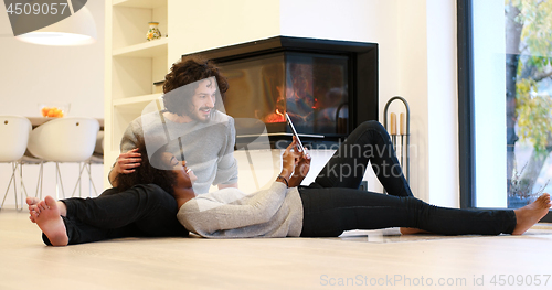 Image of Young Couple using digital tablet on the floor