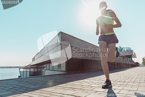 Image of Pretty sporty woman jogging at city