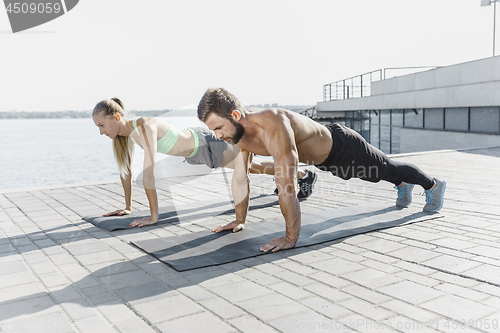 Image of Fit fitness woman and man doing fitness exercises outdoors at city