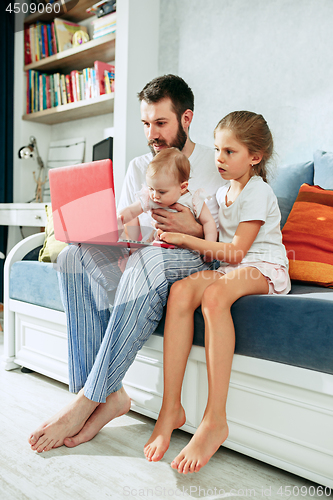 Image of Proud father holding his baby daughters at home