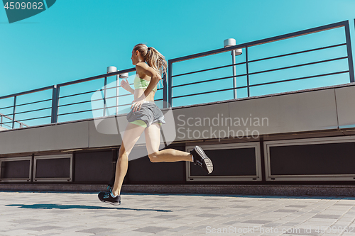 Image of Pretty sporty woman jogging at city