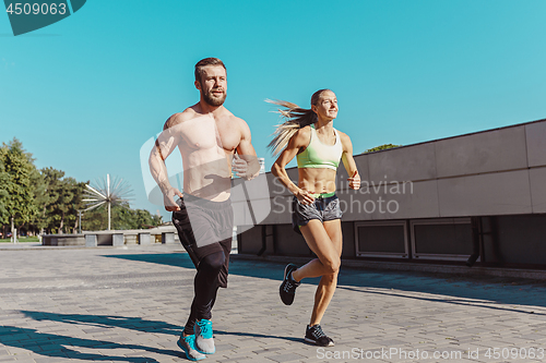 Image of Pretty sporty woman and man jogging at city