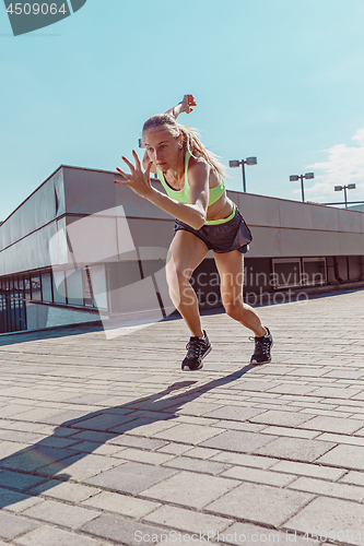 Image of Pretty sporty woman jogging at city
