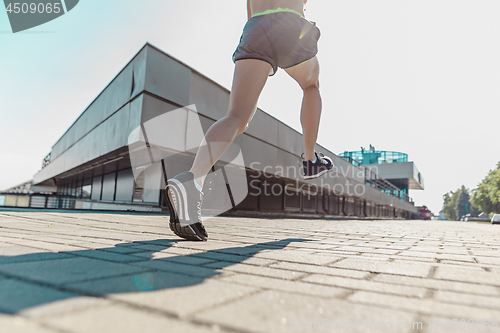 Image of Pretty sporty woman jogging at city