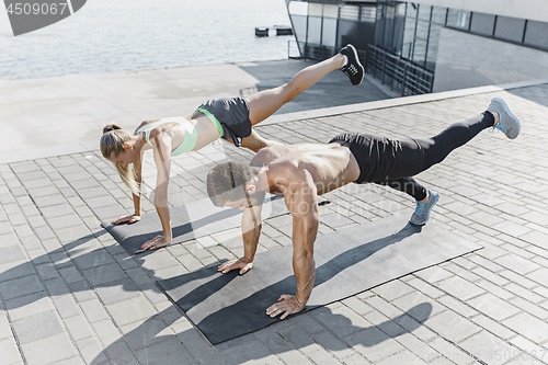 Image of Fit fitness woman and man doing fitness exercises outdoors at city
