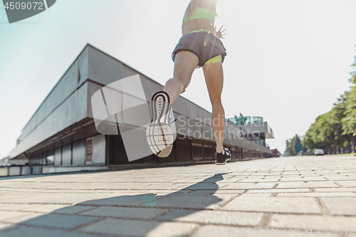 Image of Pretty sporty woman jogging at city