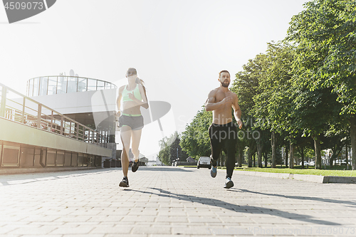 Image of Pretty sporty woman and man jogging at city