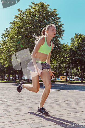 Image of Pretty sporty woman jogging at city