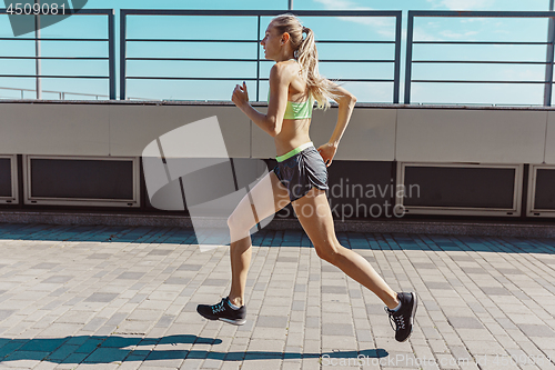 Image of Pretty sporty woman jogging at city