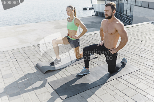 Image of Fit fitness woman and man doing fitness exercises outdoors at city