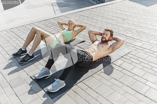 Image of Fit fitness woman and man doing fitness exercises outdoors at city