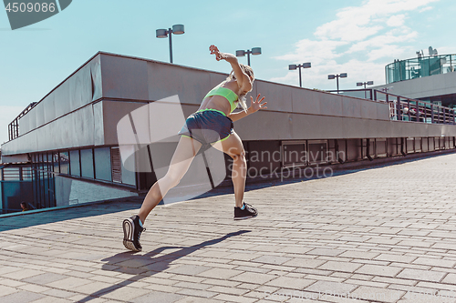 Image of Pretty sporty woman jogging at city