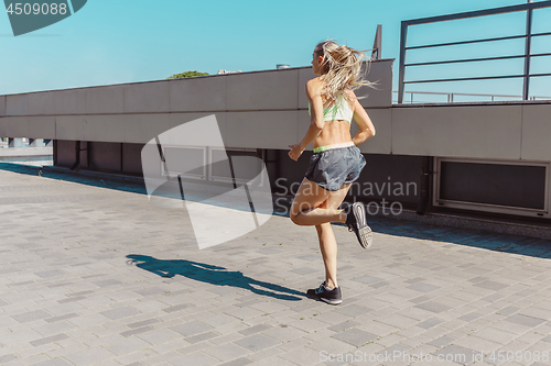 Image of Pretty sporty woman jogging at city