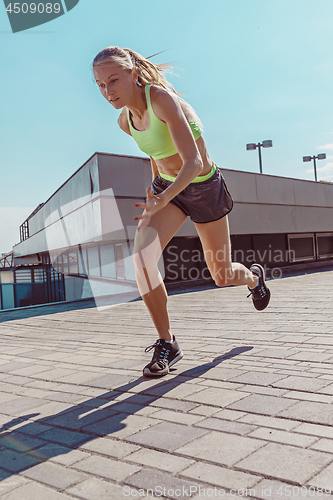 Image of Pretty sporty woman jogging at city