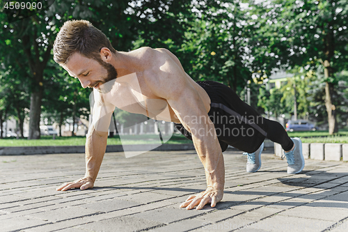 Image of Fit fitness man doing fitness exercises outdoors at city