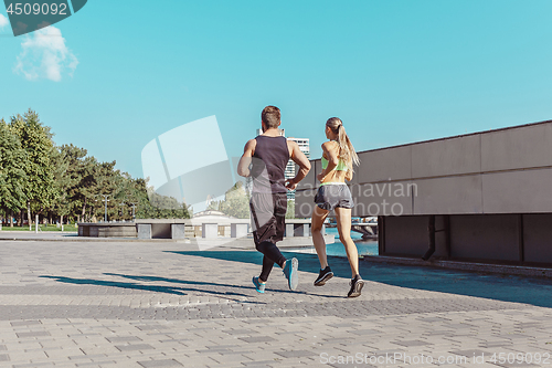 Image of Pretty sporty woman and man jogging at city
