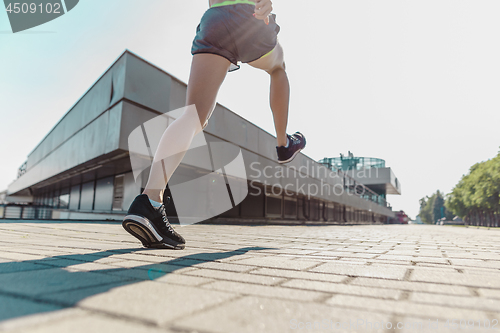 Image of Pretty sporty woman jogging at city