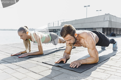 Image of Fit fitness woman and man doing fitness exercises outdoors at city