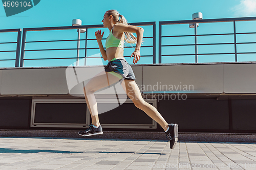 Image of Pretty sporty woman jogging at city