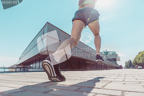 Image of Pretty sporty woman jogging at city