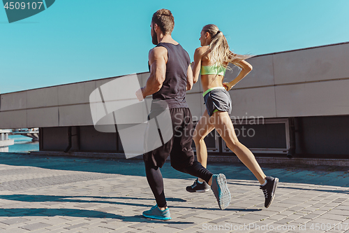 Image of Pretty sporty woman and man jogging at city
