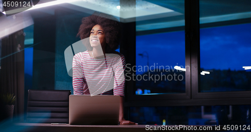 Image of black businesswoman using a laptop in night startup office